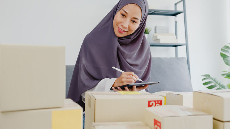 包装年轻的女商人检查产品采购订单的库存和保存到平板电脑工作在家办公办公室印尼语计算机