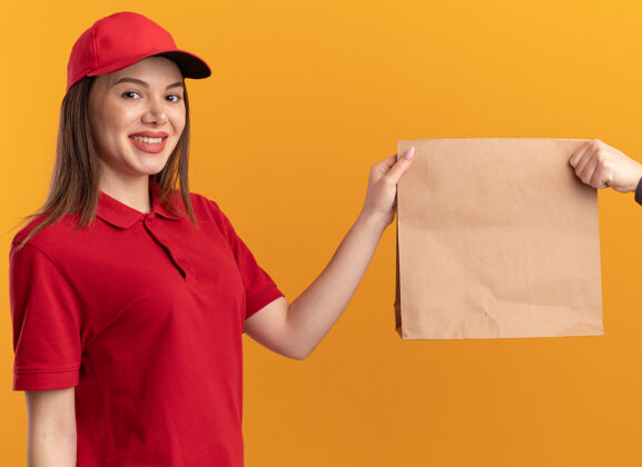 有人一位身着制服 面带微笑的漂亮女送货员把纸包递给一个看着相机的人漂亮包装橘子