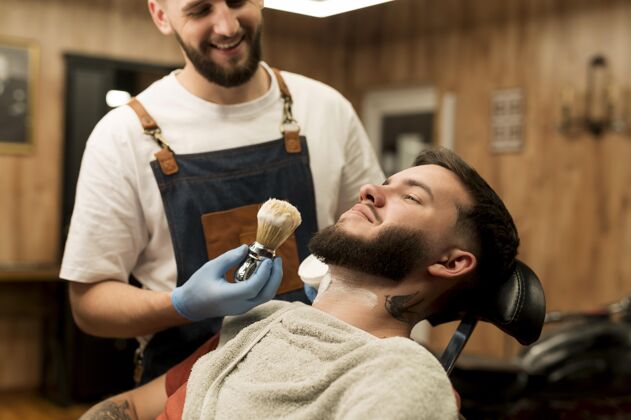 工作理发师用剃须膏勾勒男顾客的胡须轮廓理发师专业男性