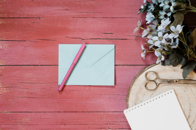女孩在浅粉色木质背景上 配上请柬信封 鲜花 钢笔和剪刀的婚礼作品尼斯爱情正方形