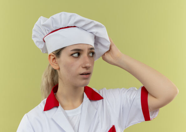 壁板年轻漂亮的厨师穿着厨师制服 看着一边把手放在绿色墙上的帽子上漂亮印象烹饪