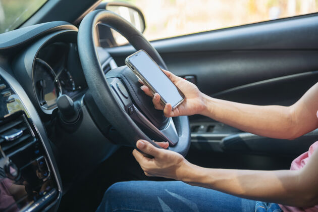 电话一个女人手持和使用手机的模拟图像 而司机的一辆车 为全球定位系统 生活方式的照片 车内 前视图与妇女手持电话手机按住触摸