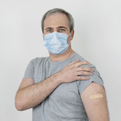 疫苗注射一个戴着医用口罩的男人在接种疫苗后手臂上有绷带免疫面罩人