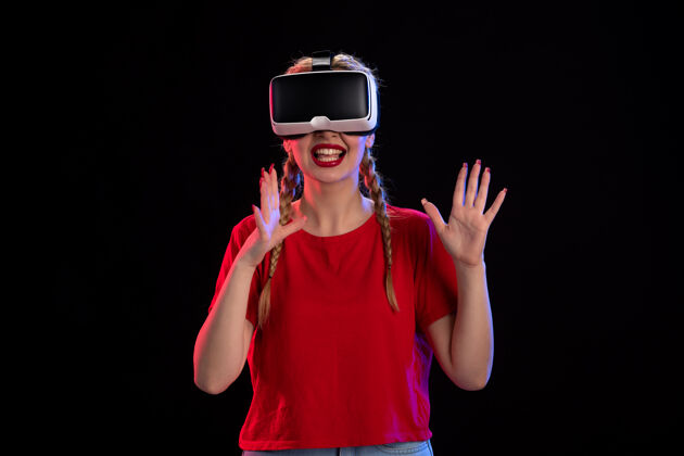 正面年轻女性在黑暗的墙上玩虚拟现实的正面图虚拟现实表情黑色