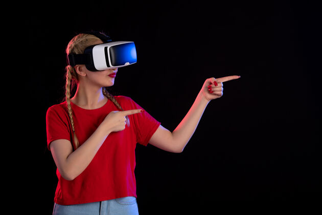游戏年轻女性在黑暗的墙上玩虚拟现实的正面图正面成人女士