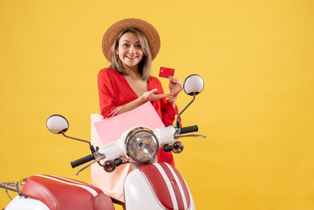 成人面带微笑的红衣女子 骑着轻便摩托车 手里拿着购物袋和购物卡红色包车辆