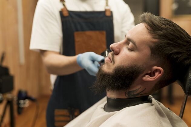 专业在理发店理胡子的年轻人雇员水平理发师