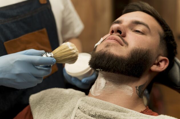 美容师理发师用剃须膏勾勒男顾客的胡须轮廓职业剃须泡沫雇员