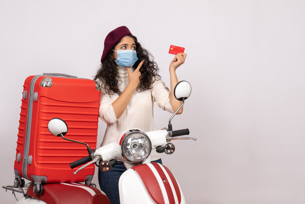 速度前视图年轻女性骑着自行车手持红色银行卡在白色背景颜色covid上-车辆病毒流行摩托车超速行驶控股病毒摩托车