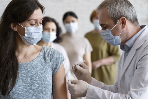 男人医生用医用口罩注射疫苗的女人医生注射女人