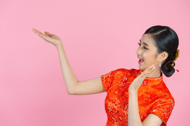复制空间美丽的亚洲女人快乐的微笑 在中国新年的粉红色背景上向你展示一些东西空虚衣服人