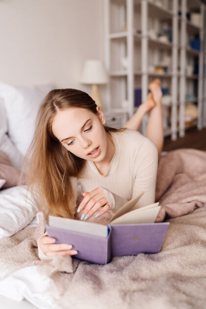 休闲年轻漂亮的女人在家里的床上享受着最喜欢的书休息家常温柔