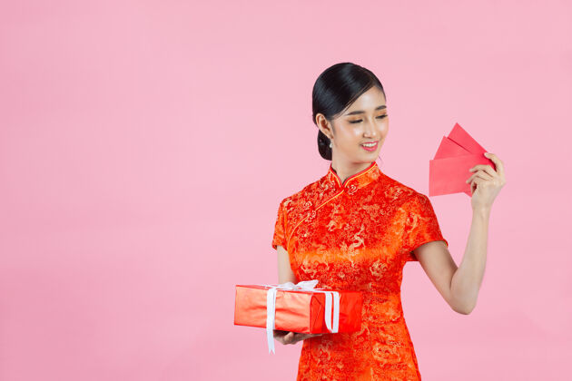 红色美丽的亚洲女人在中国的新年里展示一些东西和拿红包空白亚洲女孩