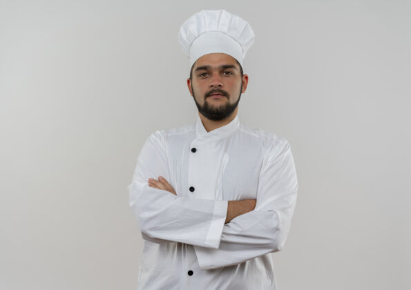 封闭自信的年轻男性厨师身着厨师制服 站在白色墙壁上 封闭的姿势 看起来与世隔绝 有复制空间姿势男性烹饪