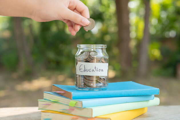 会计把存钱的硬币放在玻璃瓶中 用于概念投资 共同基金 金融和商业 放在教科书上内容：教育存钱罐子货币福利