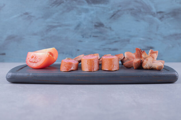 好吃把西红柿和香肠片放在黑板上小吃西红柿肉