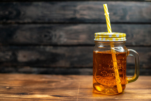 吸管正面看新鲜苹果汁内罐 用吸管放在深色鸡尾酒水果饮料上 照片颜色自由空间里面蜂蜜健康