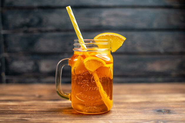 玻璃杯正面图新鲜橙汁罐内用吸管放在深色吧台上水果色照片鸡尾酒饮料蜂蜜水果正面