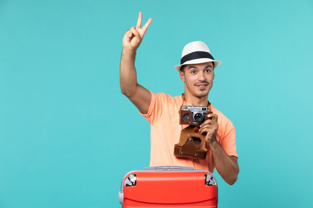包带着红色手提箱和淡蓝色相机的度假男人男性度假人