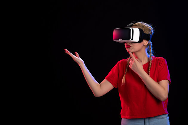 人物年轻女性在黑暗的墙上玩虚拟现实的正面图成人游戏游戏