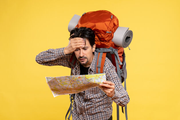 森林正面图年轻男性带着背包徒步旅行黄色背景上的观察地图公司旅行自然校园森林色彩空气徒步旅行地图旅行
