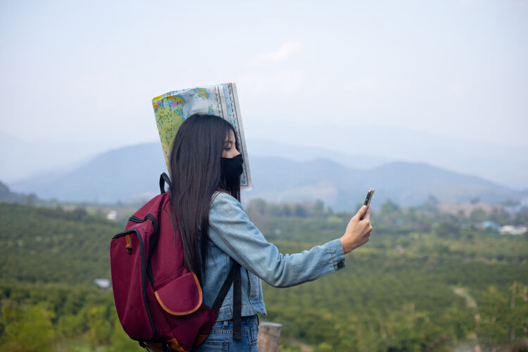 外科口罩亚洲女游客戴着口罩看手机地图水平旅游