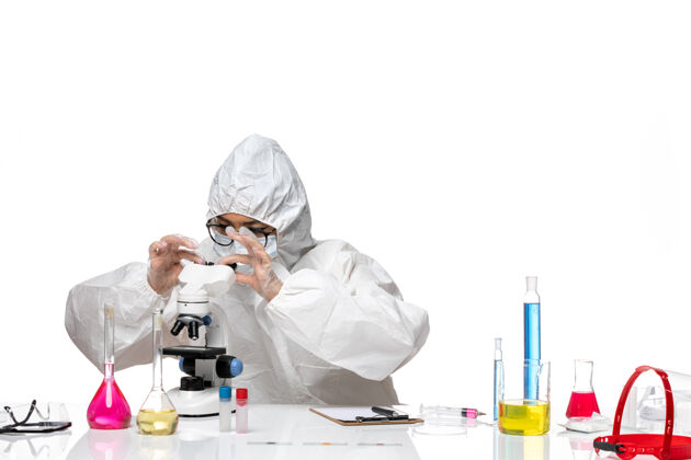 实验室正面图身着特殊防护服的年轻女化学家在白色背景病毒冠状病毒上用显微镜工作-化学实验室实验室外套化学专业