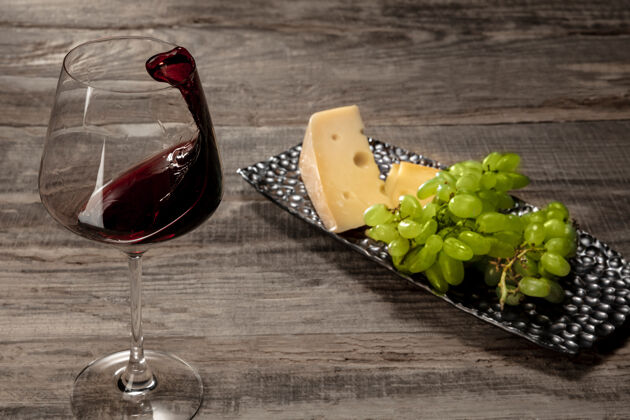 切片一瓶红酒和一杯红酒 在风化的木头表面撒上水果乳制品文化晚餐