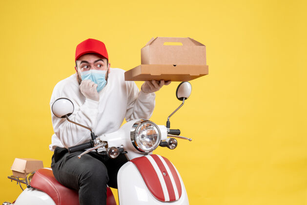 送货男快递员戴着口罩骑在自行车上拿着黄色的食品盒头盔摩托车面具