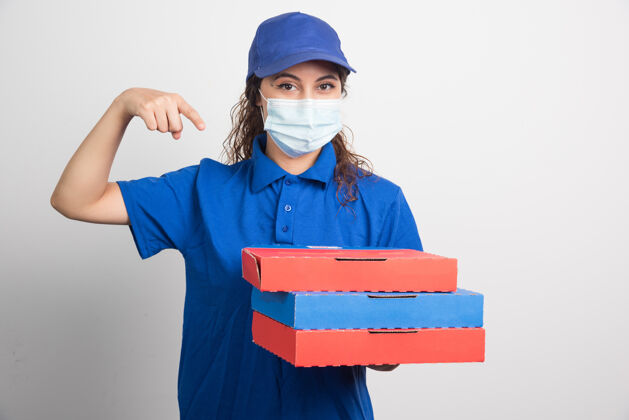 持有送比萨饼的女孩手里拿着三盒白色的医用面膜面罩女性订单