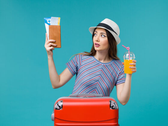微笑前景度假中的女人拿着她的果汁和浅蓝色背景的机票去度假修理工航行肖像