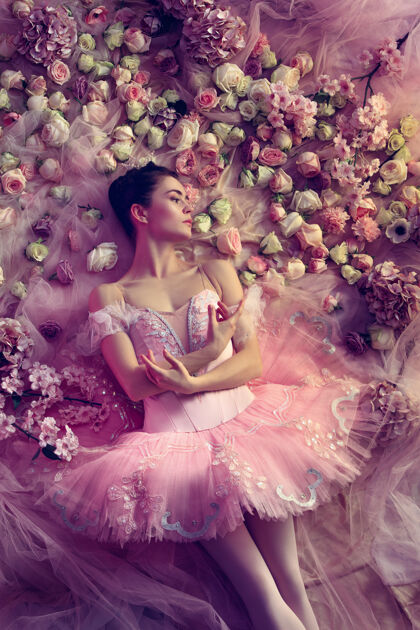年轻俯瞰美丽的年轻女子在粉红色芭蕾舞团图图周围的鲜花芭蕾舞感官动作