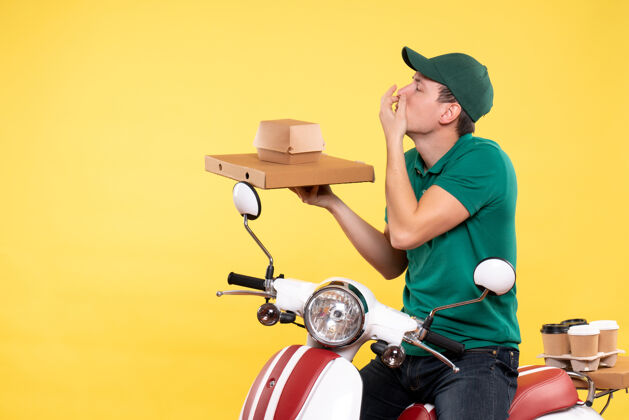 快餐正面图身着制服的年轻男性快递员手持黄色食品包装年轻男性信使食物摩托车