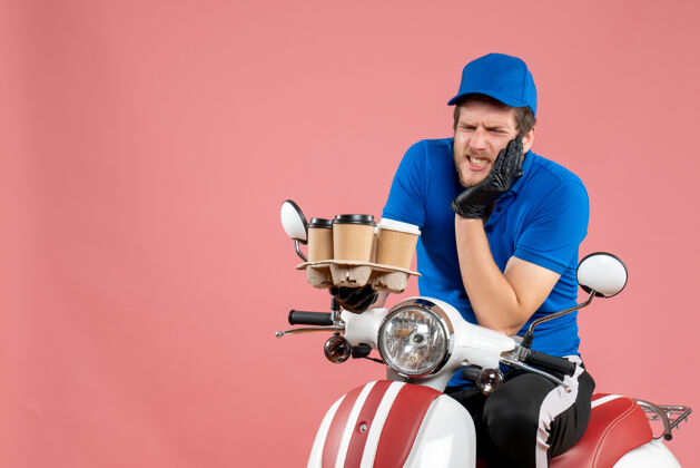 自行车正面图男性信使坐在自行车上拿着咖啡杯在粉红色送货服务人