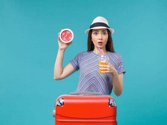 男性前景：度假中的女人拿着果汁和闹钟在蓝色的背景上航行度假海上旅行微笑人旅行