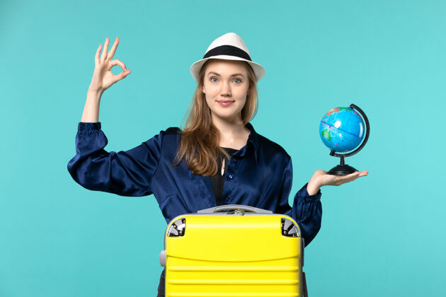人正面图年轻女子手持地球仪 准备在蓝色地板飞机上度假女性度假之旅远航大海女性美丽微笑
