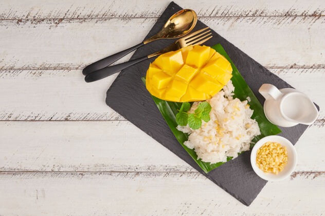 泰国甜点熟透的芒果和糯米加椰奶在石头表面 泰国甜点在夏天的季节食物木头夏天