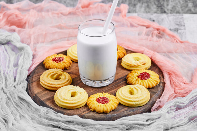 分类各式饼干和一罐牛奶放在木板上 还有桌布桌子篮子燕麦片