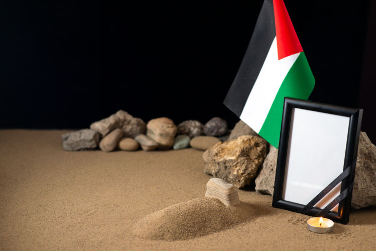 石头小坟上挂着巴勒斯坦国旗 黑桌上放着石头巴勒斯坦战死战争旗帜死亡