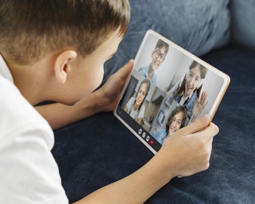 水平男孩通过视频通话和他的朋友在平板电脑上交谈孩子通讯科技