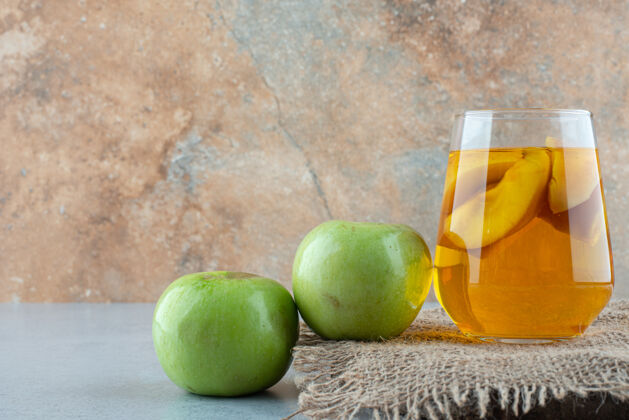 果汁一杯果汁和新鲜苹果放在粗麻布上苹果玻璃杯生的