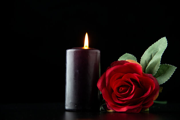 死亡黑暗表面上有红玫瑰的黑暗蜡烛的正视图玫瑰烛光黑暗