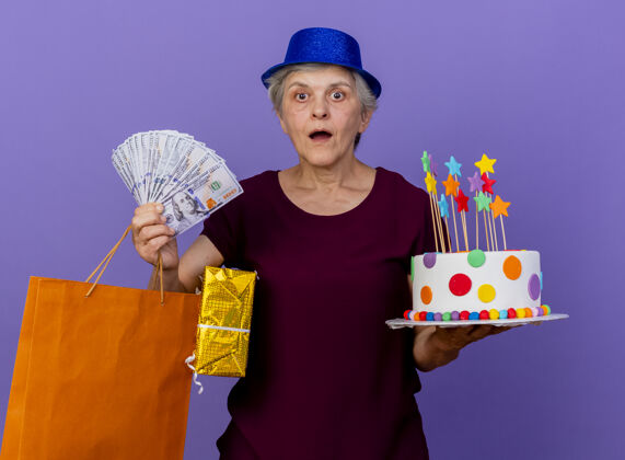惊喜惊讶的老太太戴着聚会帽拿着生日蛋糕钱礼盒聚会老人帽子