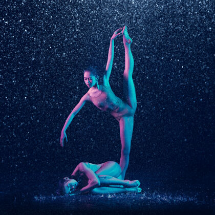 表演两个年轻的女芭蕾舞演员在水滴下现代在一起灵活