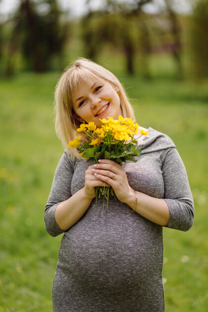 孕妇年轻的金色孕妇身着灰色连衣裙 怀孕的女孩在春天散步 母性观念灰色夹克母亲健康