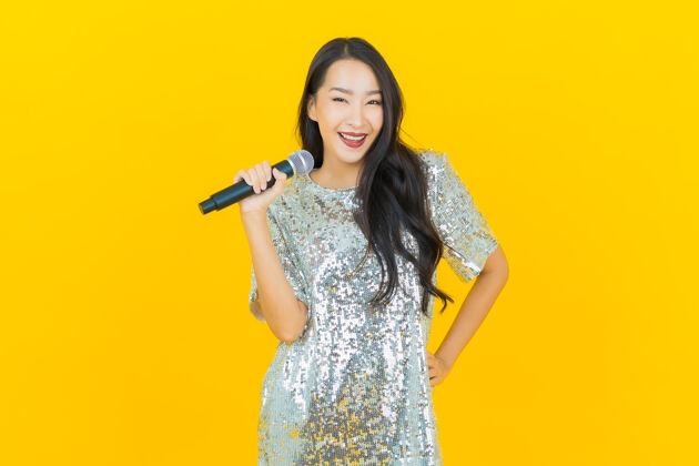 音乐肖像美丽的亚洲年轻女子用黄色麦克风唱歌亚洲麦克风女性