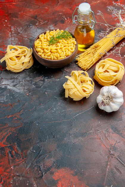 美食在混合色背景上的棕色碗和葱柠檬蒜油瓶中的三块生肉片和蝴蝶面的垂直视图背景生菜蔬菜