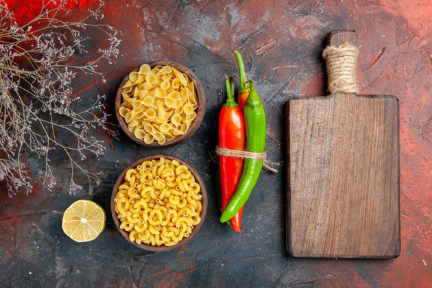 食物不同颜色和大小的生面团辣椒的俯视图 用绳子和木制砧板在混合色背景上相互捆扎在一起混合菠萝板