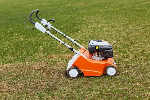 马达橙色的割草机站在绿草地上剪子拖拉机机器