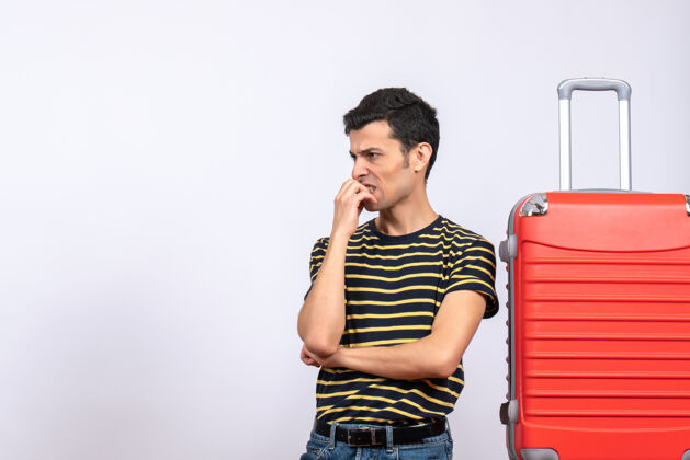 前面正面图：穿着条纹t恤和红色手提箱的年轻人在思考电话手成人